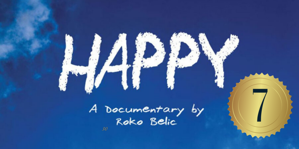 Happy film poster. Bright blue sky is the background with white clouds at the edges. The word Happy is large across the center in white fluffy letters, all capitalized. Below that, white text reads: A Documentary by Roko Belic. In the upper left-hand corner is a gold circle with the 7 inside. 