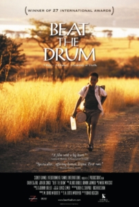 Official film poster for "Beat the Drum". It shows a young Black South African boy walking through a dry landscape. 